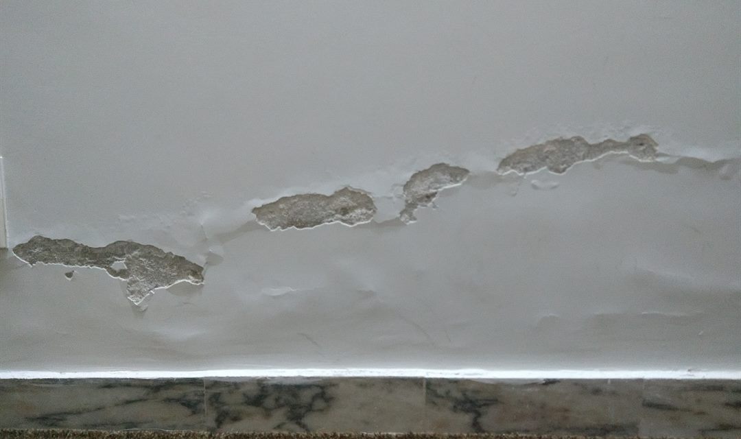 Innenwand mit abplatzendem Putz im unteren Wandbereich durch aufsteigende Feuchtigkeit